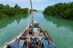 two people are sitting on the back of a boat in the middle of green water