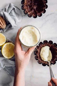 a person holding a spoon in front of some desserts on a marble counter top