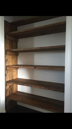 an empty shelf in the corner of a room with white walls and wooden shelves on both sides