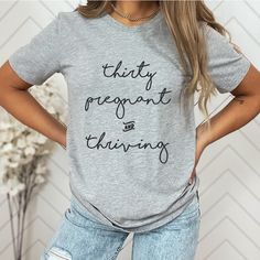 a woman standing with her hands on her hips wearing a grey shirt that says, thirty pregnant and thinking