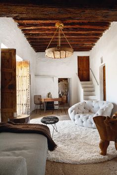 a living room filled with furniture and a chandelier hanging from the rafters