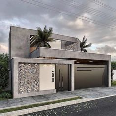 a modern house with two garages and palm trees on the side of the road