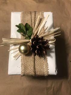 a present wrapped in burlap and tied with twine, pineconis and ribbon