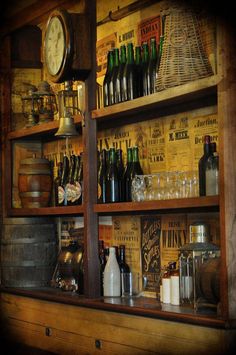 an old fashioned bar with lots of bottles and glasses on the shelves in front of it