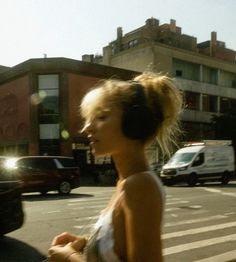 a woman walking down the street with headphones on