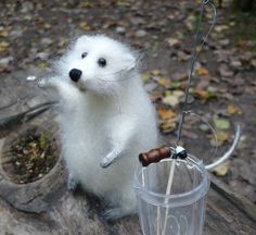 an animal that is standing next to a glass on a tree stump with a stick in it's mouth