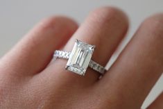 a woman's hand with an engagement ring on it and a diamond in the middle