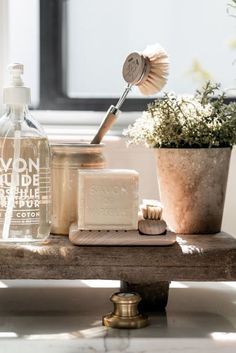 a wooden table topped with lots of bottles and containers filled with cleaning products next to a potted plant