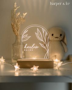 a white light up sign sitting on top of a table next to a teddy bear