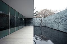 the reflection of trees in the water is seen on the glass wall next to the pool