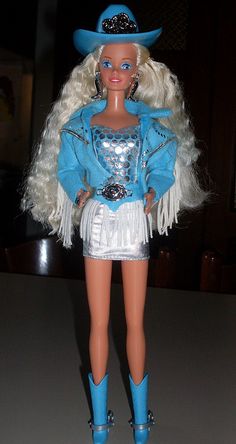 a barbie doll wearing a blue and white outfit with fringes on her skirt, boots and hat