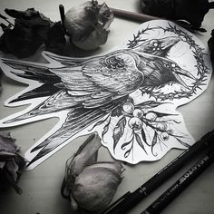 a black and white photo of a bird on a piece of paper next to some flowers