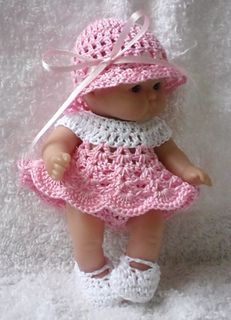 a small doll wearing a pink crocheted dress and hat