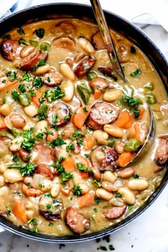 a bowl filled with beans, sausage and carrots