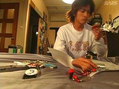 a young man sitting at a table with scissors and other items on the table in front of him