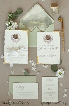 the wedding stationery is laid out on top of each other with flowers and greenery