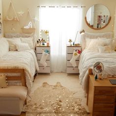 two beds in a bedroom with white comforters and gold decorations on the headboards