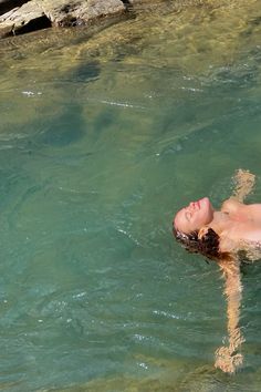 a person swimming in the water near some rocks