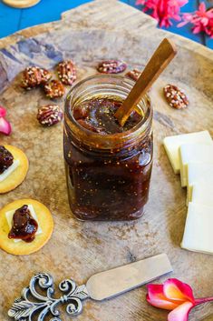 a jar of jam sitting on top of a cutting board next to cookies and cheese