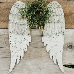 two white angel wings sitting on top of a wooden table next to a planter