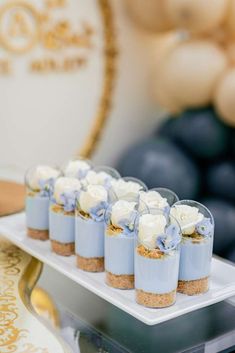 small desserts are arranged on a white platter with blue and white flowers in them