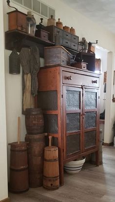 an old wooden cabinet sitting in the middle of a room filled with pots and pans