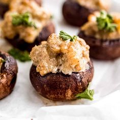 small stuffed mushrooms with crumbs and garnishes on white parchment paper