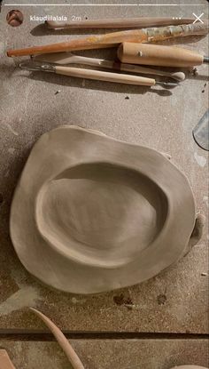 a clay bowl sitting on top of a table next to other tools and pottery items