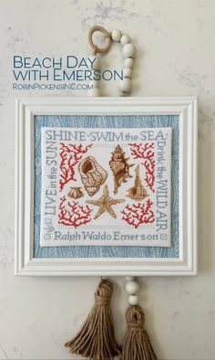 a cross stitch pattern hanging on the wall next to a pair of scissors and beads