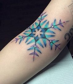 a colorful tattoo on the arm of a woman with an arrow and snowflake design