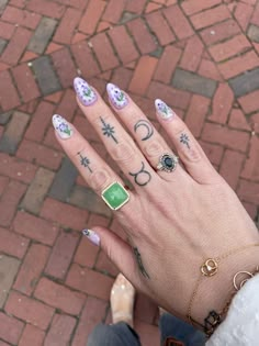 a woman's hand with tattoos and rings on her fingers, holding onto the ground