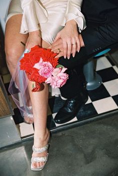 a man and woman sitting next to each other on a checkered floor with flowers in their lap