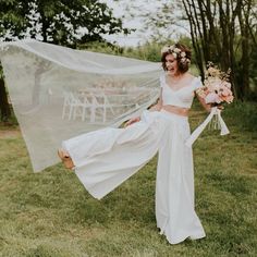 a woman in a white dress holding a veil over her head