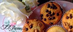 four chocolate chip muffins on a pink plate with white flowers in the background