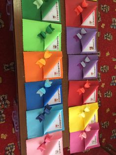 several different colored pieces of paper are arranged on a wall in the shape of bows