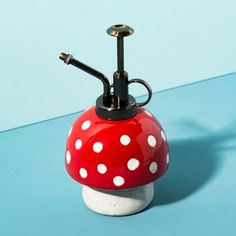 a red and white mushroom shaped lamp on a blue surface with polka dot dots in the shade