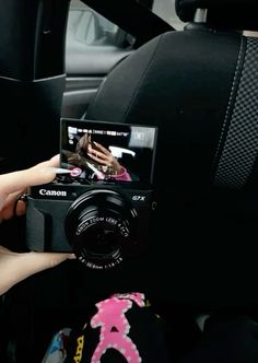 a person holding up a camera to take a picture in the car with her hand