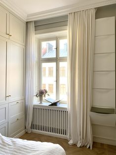 a bedroom with white curtains and a window sill next to a radiator