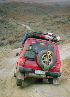 a red jeep driving down a dirt road