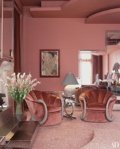 an elegant living room with pink walls and furniture in the center, along with a large mirror on the wall