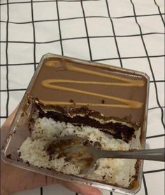 someone is holding up a half eaten chocolate cake with white rice and caramel icing