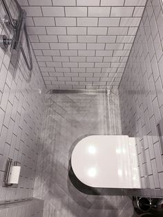 a white toilet sitting inside of a bathroom next to a walk in shower head mounted on a wall