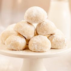 powdered sugar donuts stacked on top of each other on a white cake plate