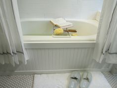 a pair of slippers sitting on top of a bathroom floor next to a bath tub