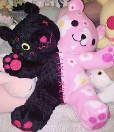 several stuffed animals are lined up on the floor, including one black cat and one pink teddy bear