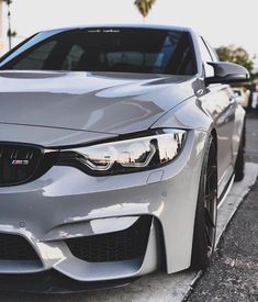 the front end of a silver car parked on the side of a street next to a curb