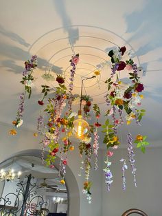 a chandelier with flowers hanging from it's ceiling in front of a mirror