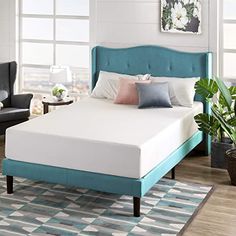 a bed with blue headboard and white sheets in a room next to a window