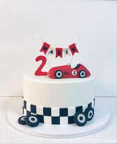 a birthday cake decorated with a race car and number two on top is ready to blow out the candles