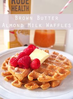 a white plate topped with waffles covered in syrup and raspberries next to a bottle of milk